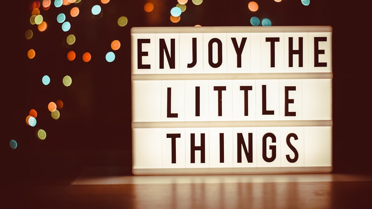 a lit up sign that says enjoy the little things